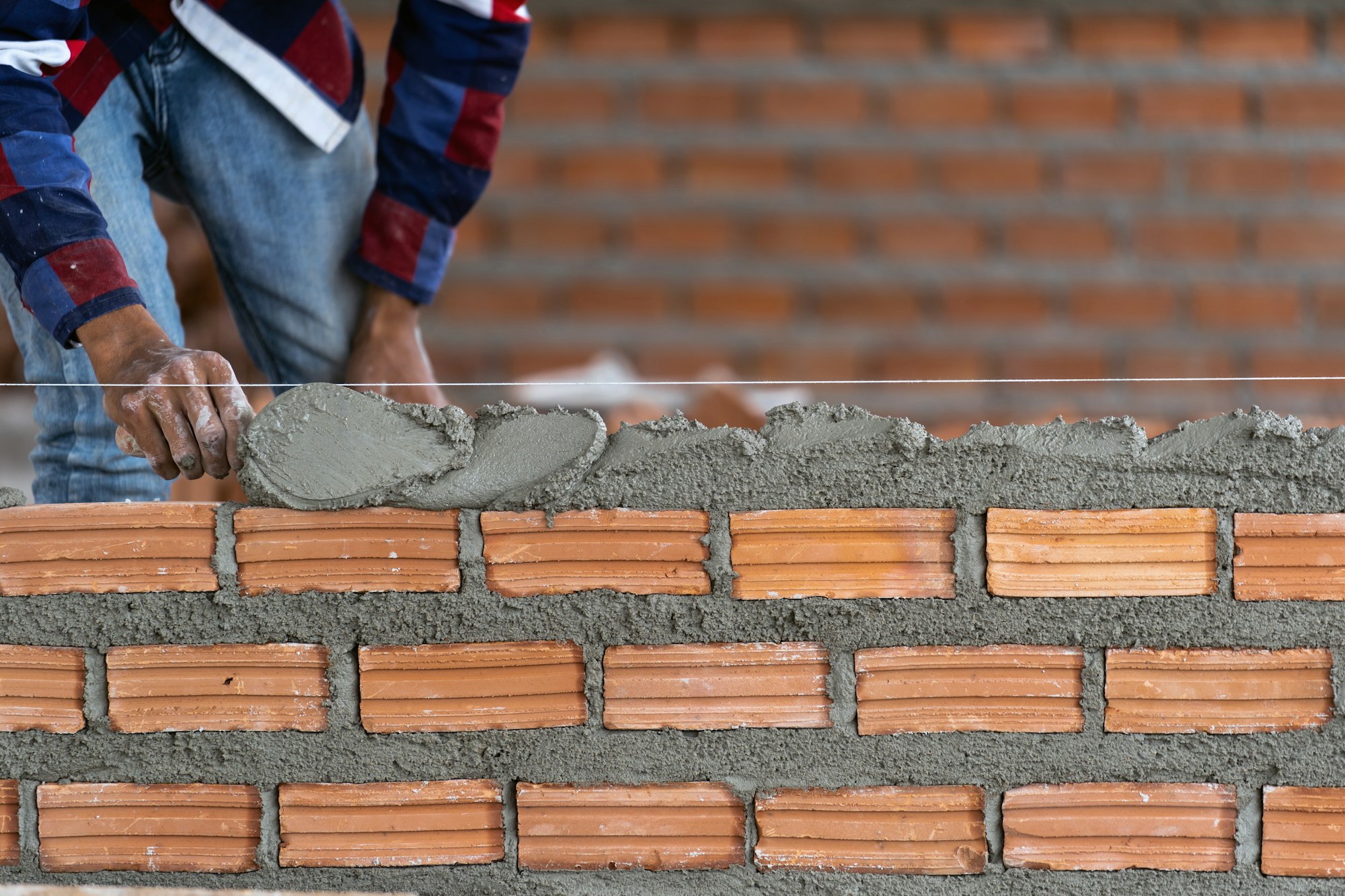 Closeup hand professional construction worker laying bricks in new industrial site.